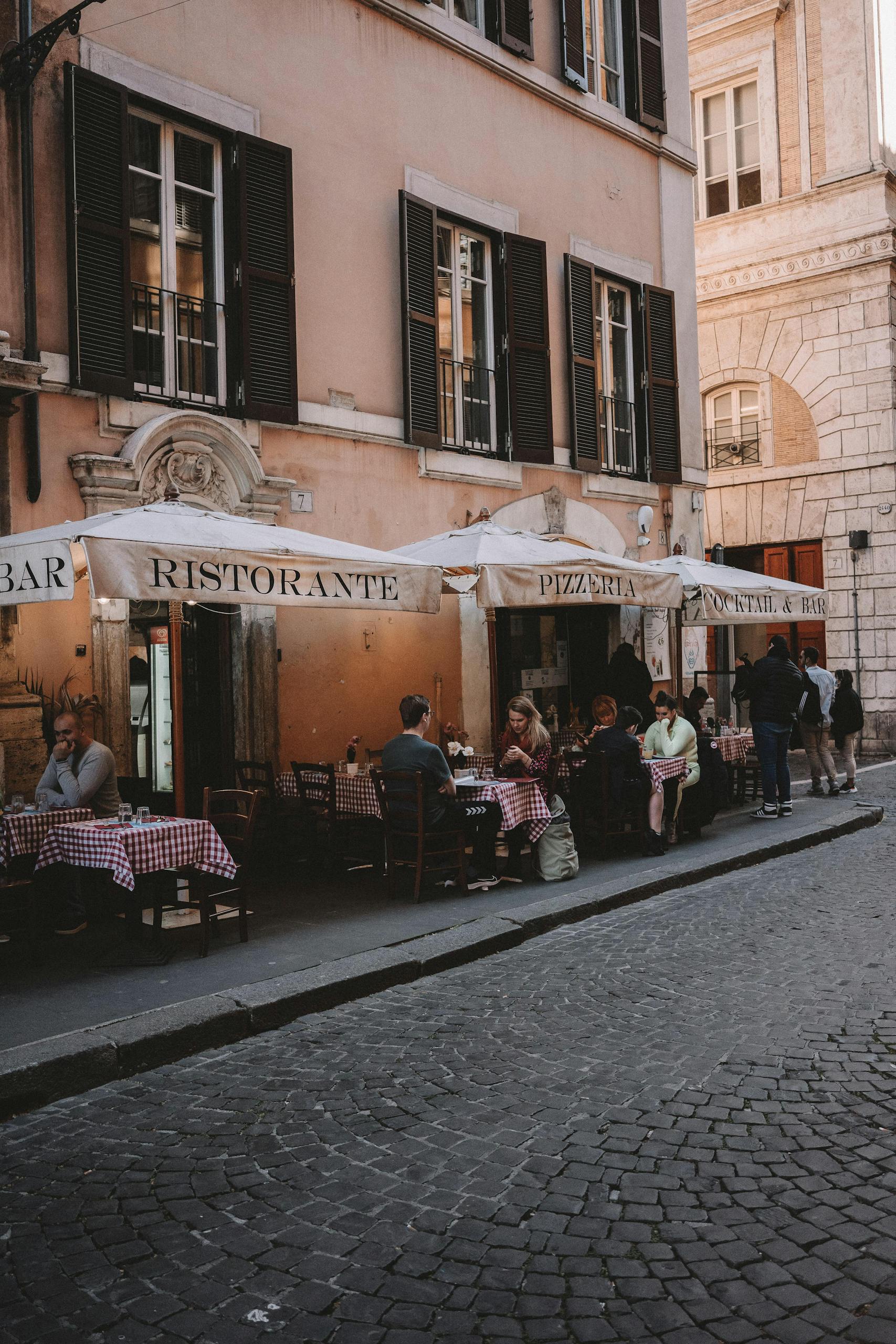 Quaint outdoor dining scene at a traditional Roman restaurant on a cobblestone street.